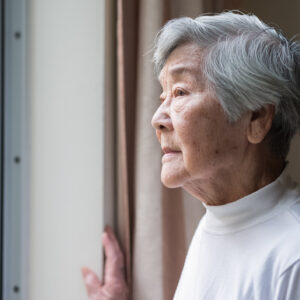 Chinese senior woman looking outside.